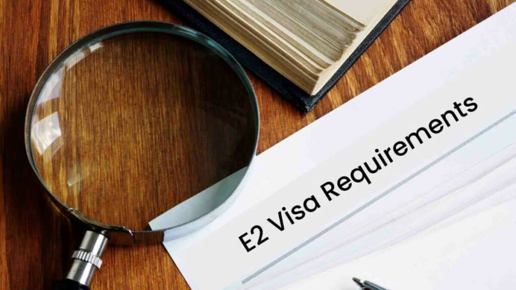 E2 Visa requirements documents with magnifying glass