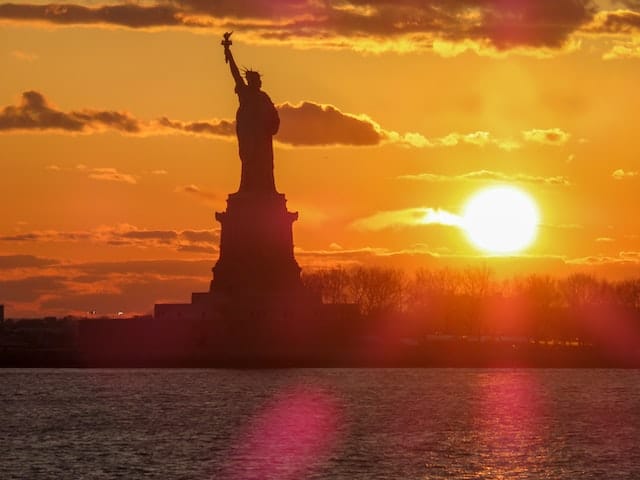 Liberty statue being captured by E2 Visa applicants during sunset