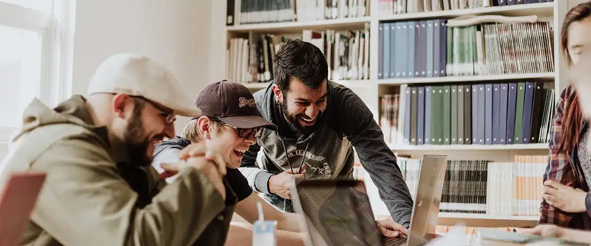 Colleagues smiling around a laptop in an office