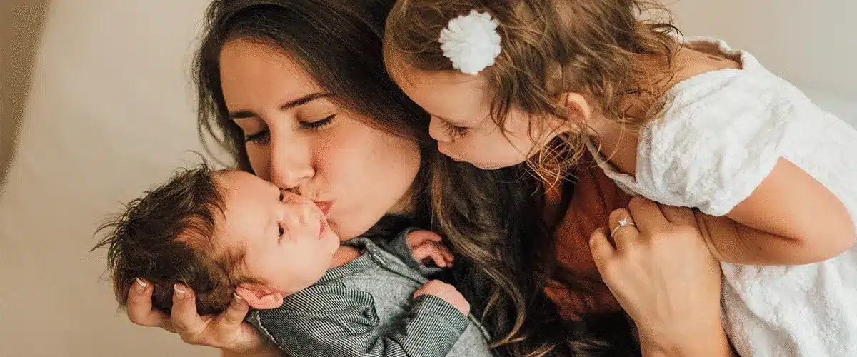 A mother holding her baby beside her young daughter