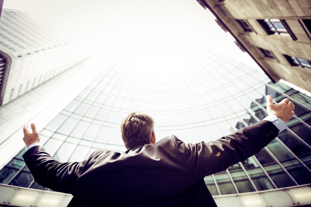 A man opens up with wide arm looking at the sky and buildings