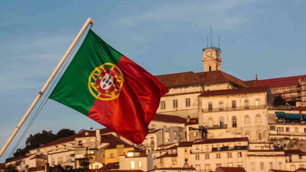 Portugal E2 Visa flags with building behind it